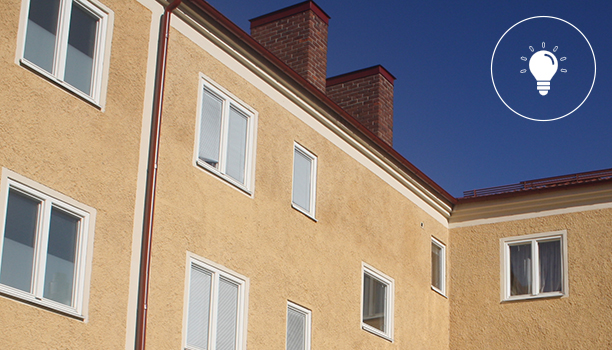 Hustak på flerbostadshus mot blå himmel