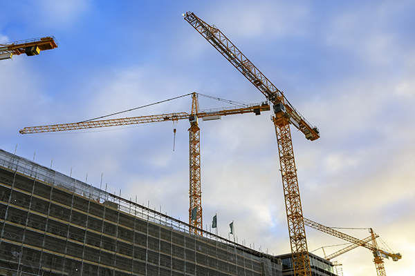 Fasad med tre byggkranar i bakgrunden