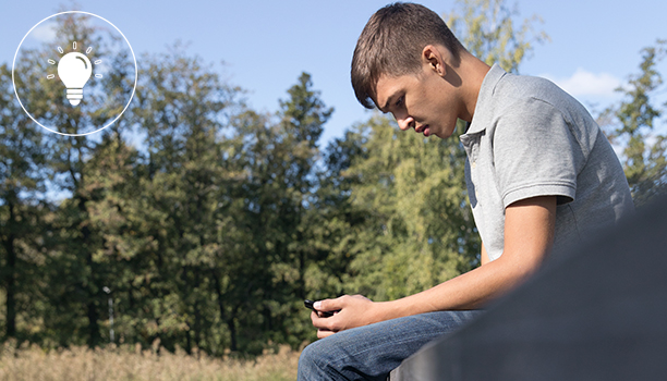 Pojke sitter på en brygga läser på sin mobiltelefon