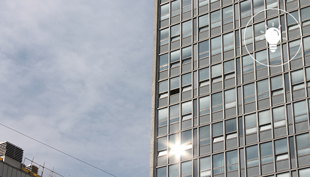 Skrapan, som är ett höghus i glas och metall, reflekterar sommarsol.