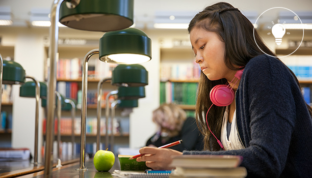 Student som sitter i läsesal i bibliotek