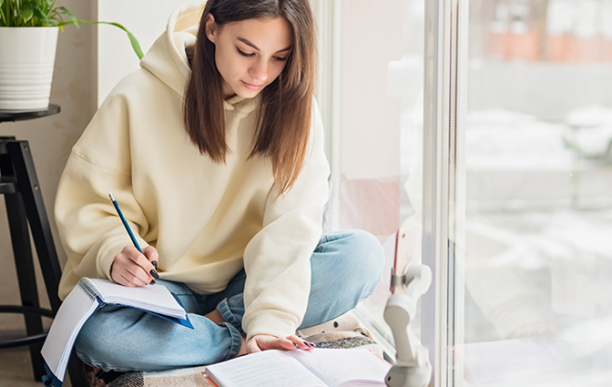 student som sitter i ett fönster och läser